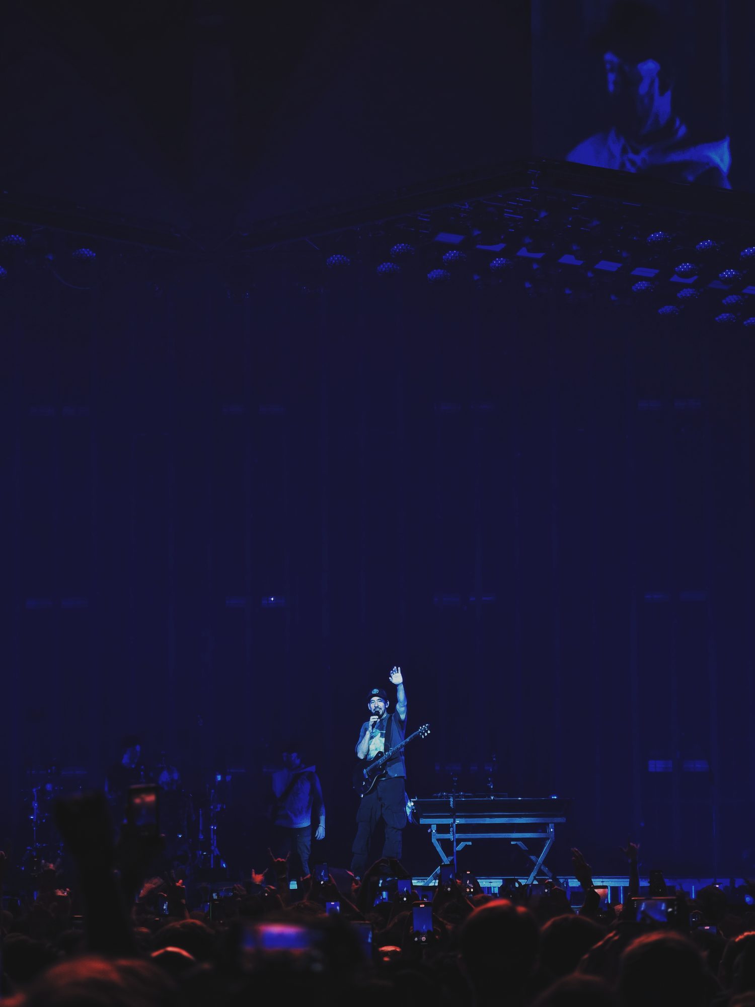 Shinoda, hand up, the room held in blue.